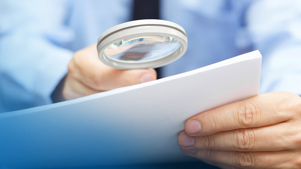 A man looking over a document with a magnifying glass